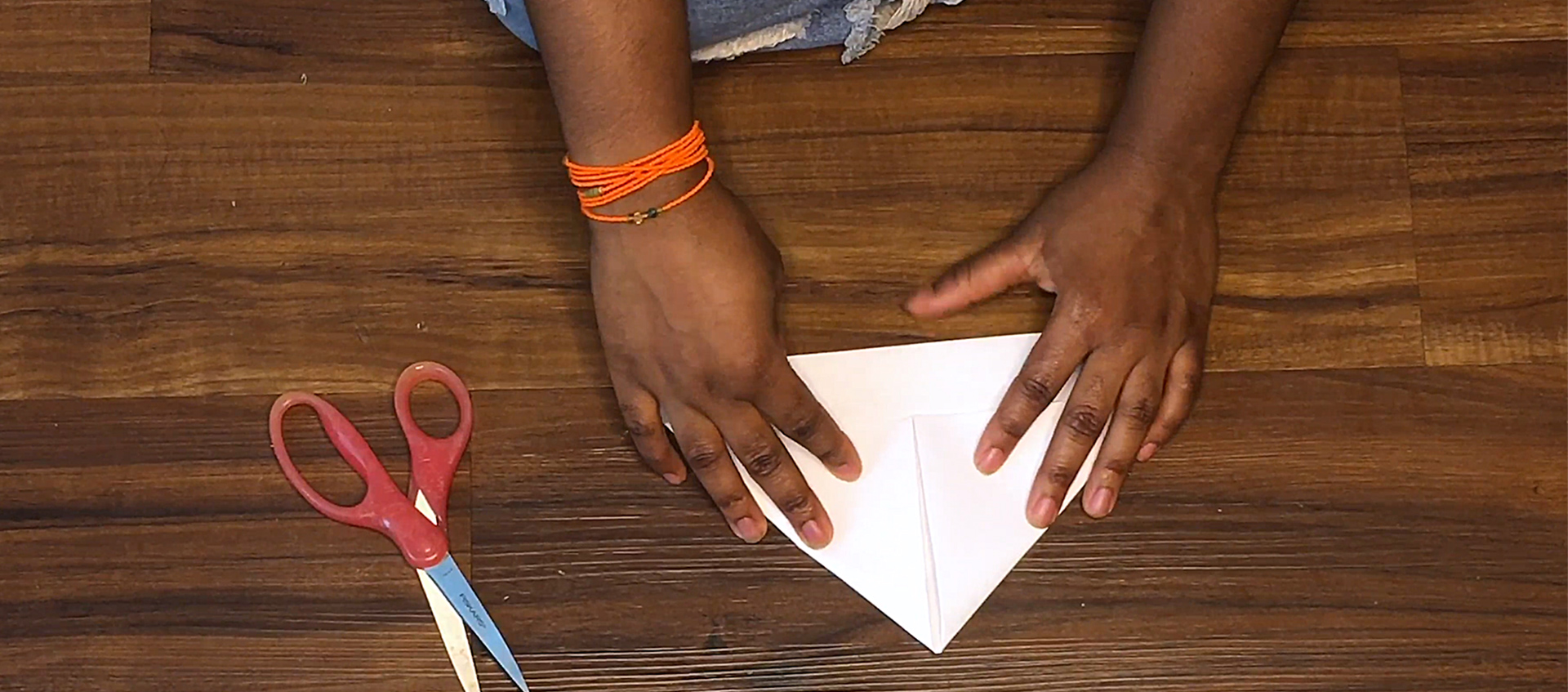The hands of Claudia Owusu making a paper boat