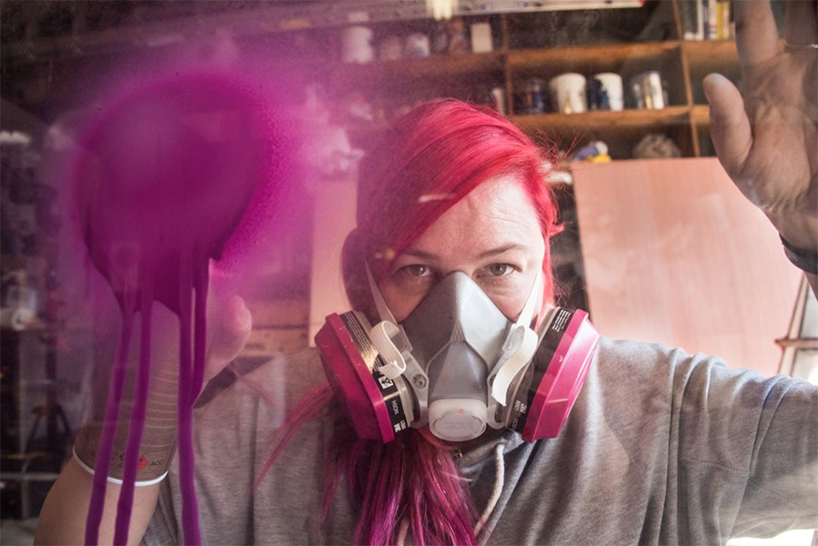 Image of artist Stephanie Rond in ventilation mask while she paints