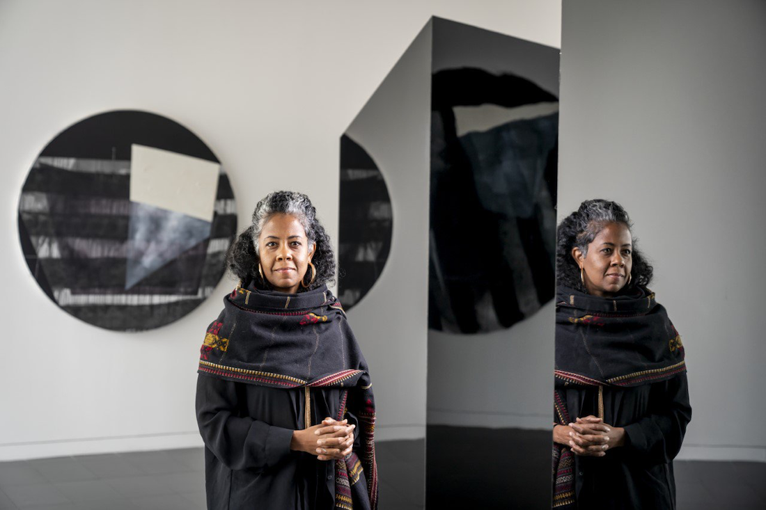 Artist Torkwase Dyson stands in a gallery installed with her work