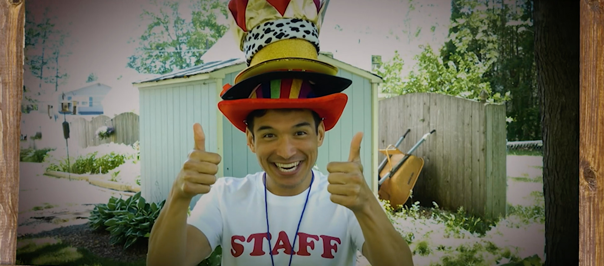Actor Zachary Noah Piser smiles and wears a pile of hats and gives two thumbs up during an episode of PBS Thirteen's Camp TV