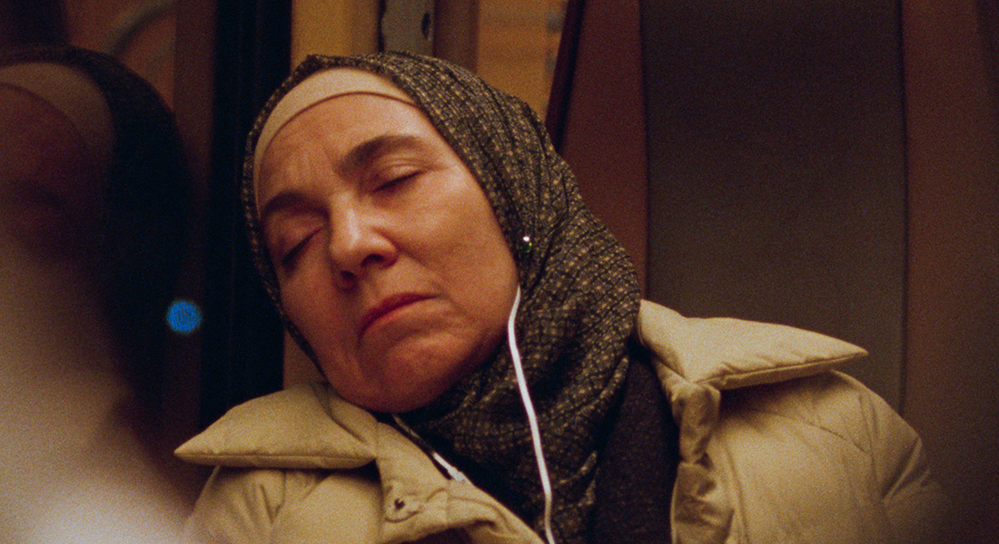 Khadija sleeps on the train with headphones on