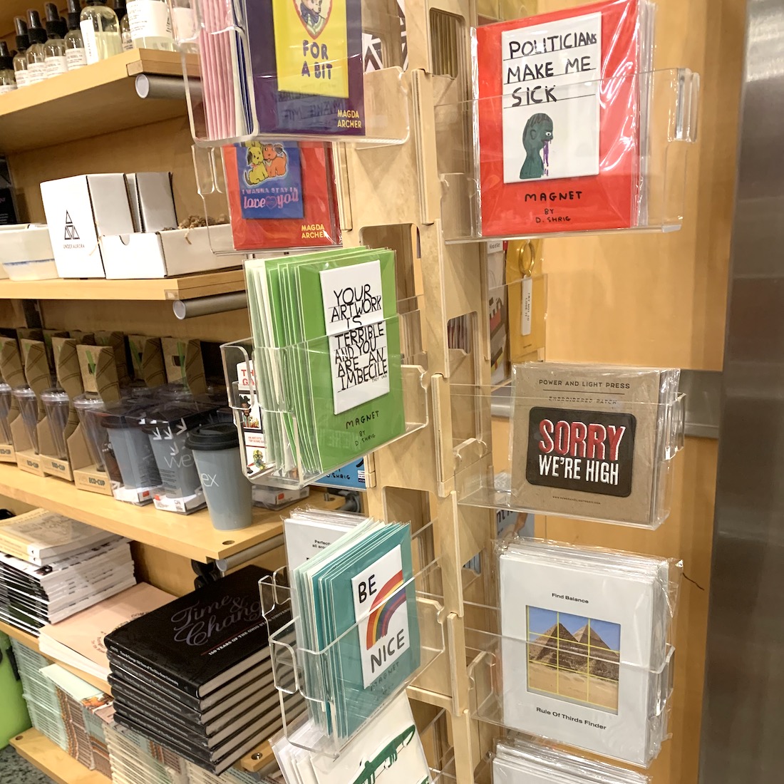 Small gift items in a spinner rack with shelves full of small retail items in the background