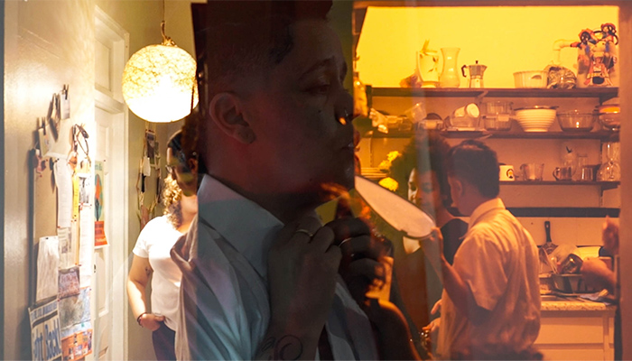 A close-up image of Awilda donning a shirt and tie is juxtaposed against an image of people in a domestic space