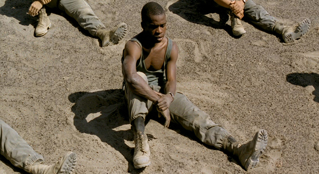 A soldier sits in the sand along with his troop