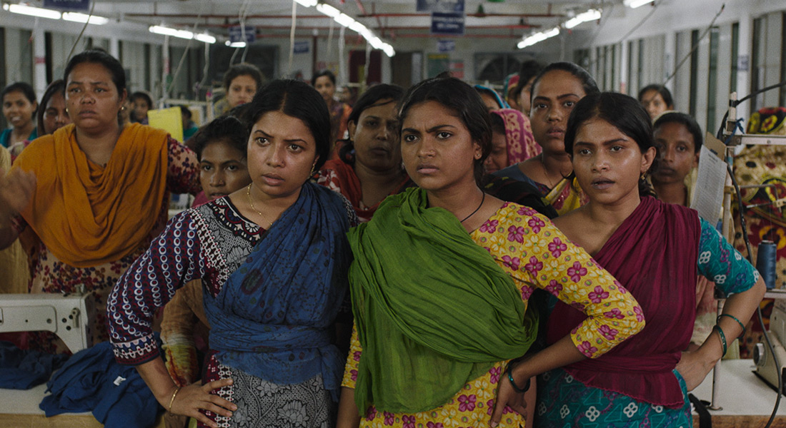 A group of women in a textile factory look out disapprovingly