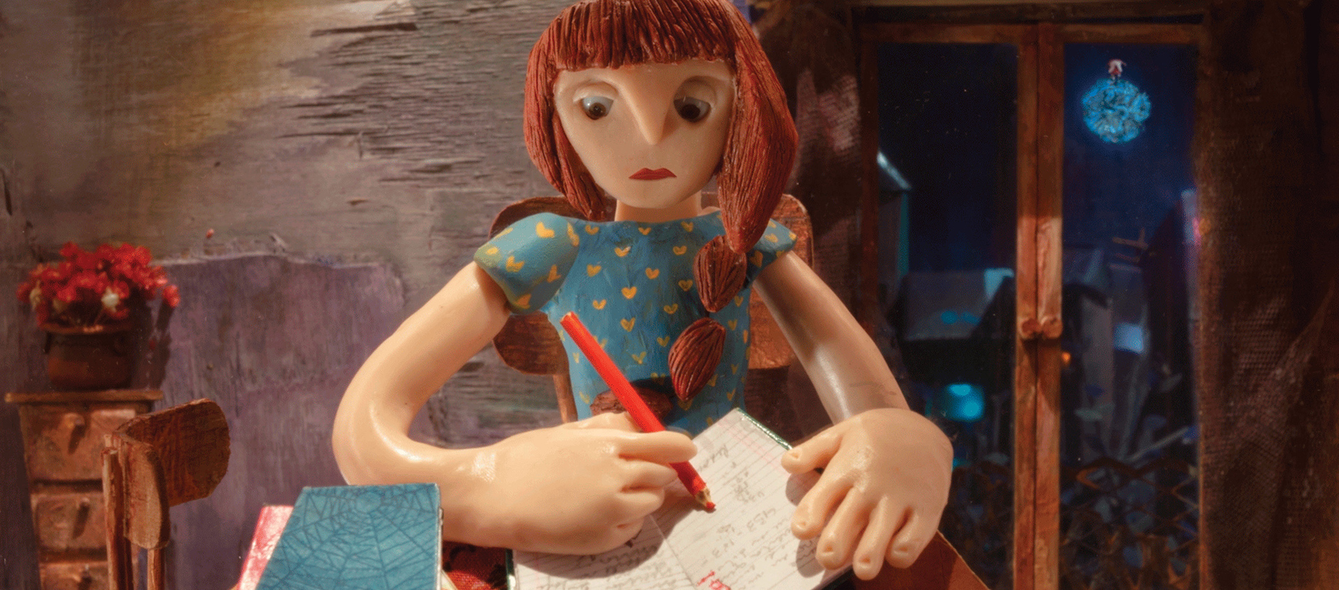 A woman, constructed from clay, sits at a desk and writes in a journal.