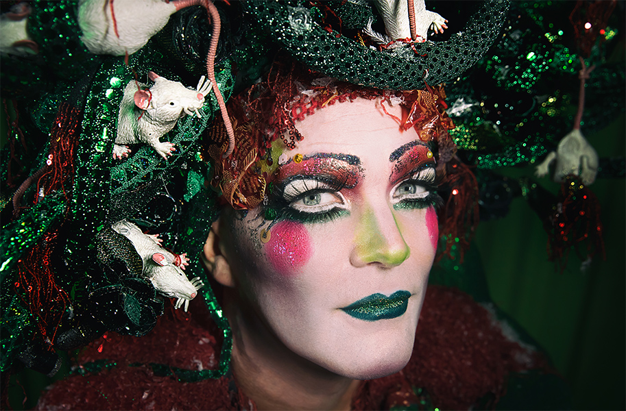 Taylor Mac wears a snake and rat headdress while wearing festive, glittery makeup.