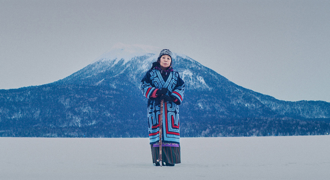 A woman with patterned clothes standing alone in a snowy landscape.