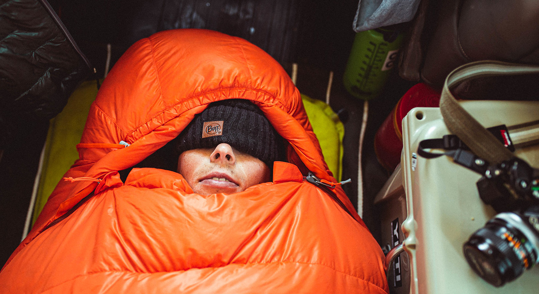 A person in a sleeping bag showing only his mouth and nose.