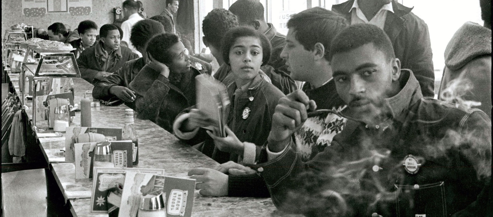 A black and white photo by Danny Lyon of Black men and women at a lunch counter