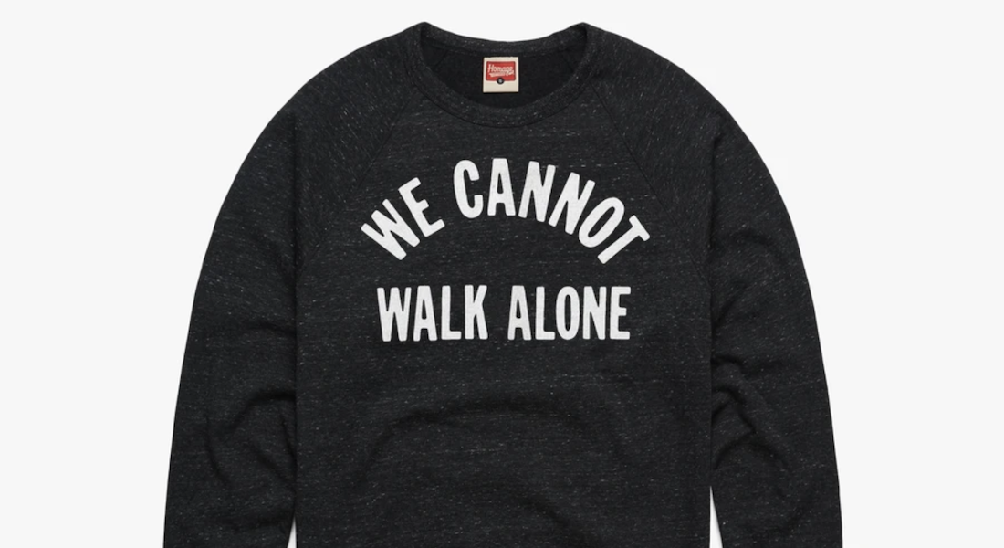 Long sleeve dark gray t-shirt by Homage with a partial quote by Martin Luther King Jr. in white all caps: "We cannot walk alone"