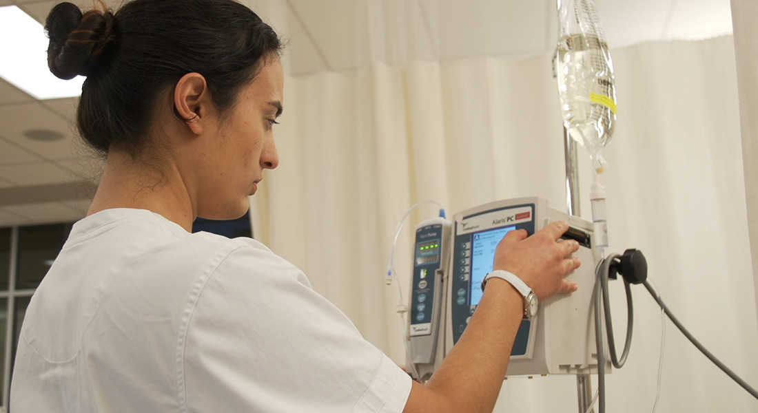 A health-care worker adjusts a setting on an IV machine