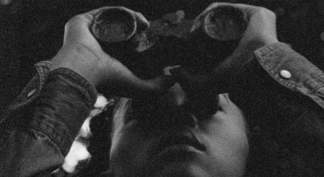 A black and white image of a person looking skyward through a pair of binoculars.