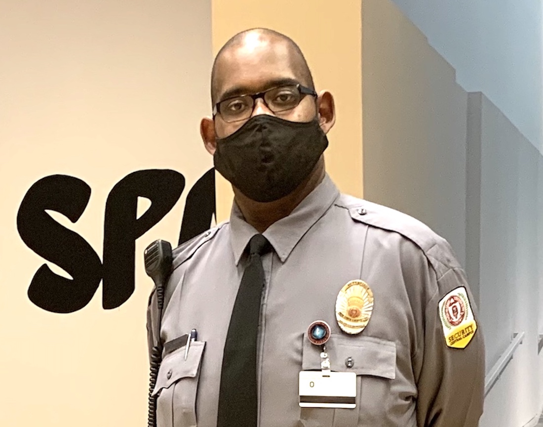 Security Supervisor Nick Morris in his uniform and a black face mask stands at the entrance to the Wexner Center for the Arts galleries