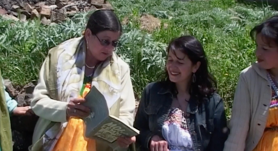 Two women sharing a book out in the fields.