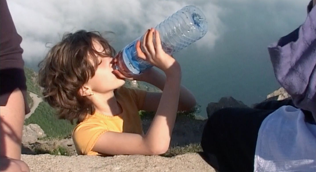 A girl drinking water facing the sun.