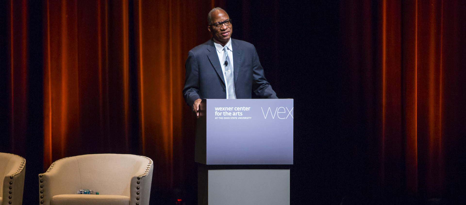 Wil Haygood stands at a podium on the stage of Mershon Auditorium