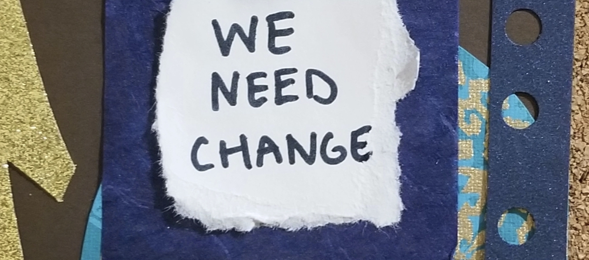 Mixed paper collage with "We need change" handwritten on a piece of paper at the center