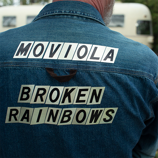 An image of a blue jean jacket with the words Moviola and Broken Rainbows on the back