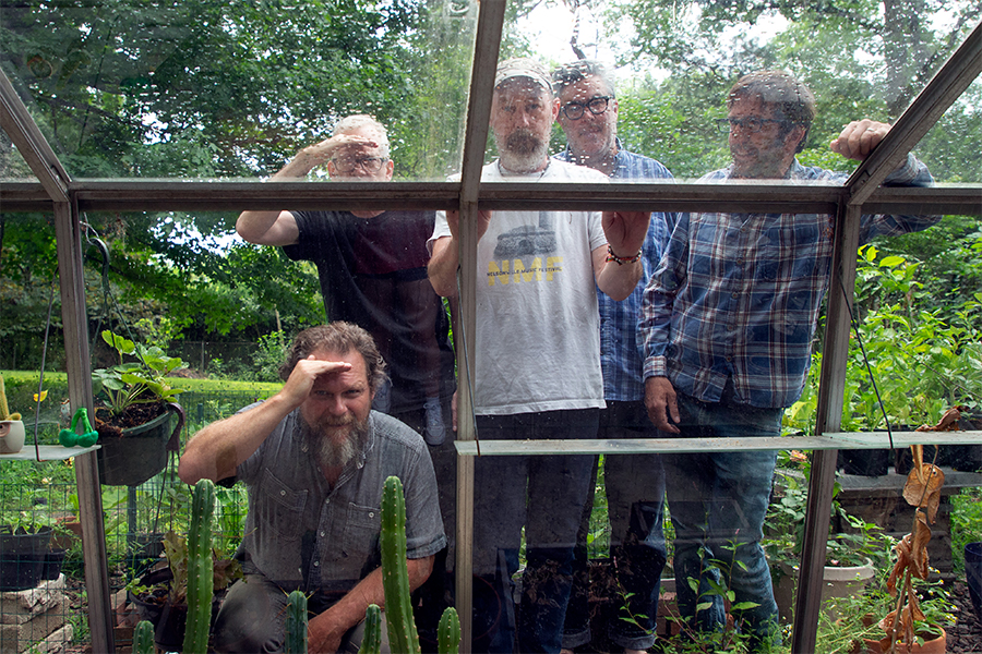 Five members of Moviola standing in the outdoors looking into a set of windows