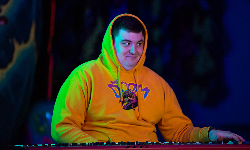 A person in a yellow hoodie at a keyboard
