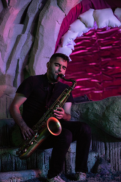 A person in a black t-shirt playing saxophone