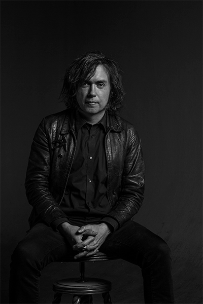 Black and white photo of author and editor Chet Weise seated in a leather jacket