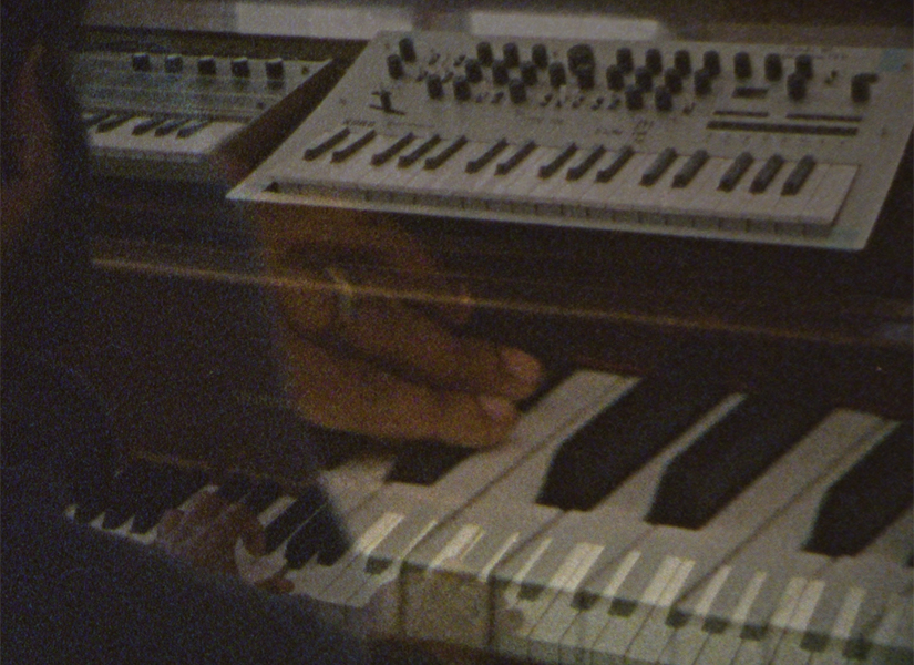 A close-up of piano keys and keyboards with a ghostly image of hands touching the keys