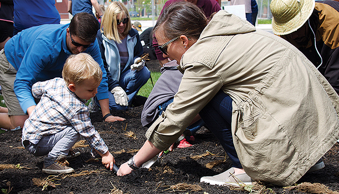 a group of people and a child, digging a garden