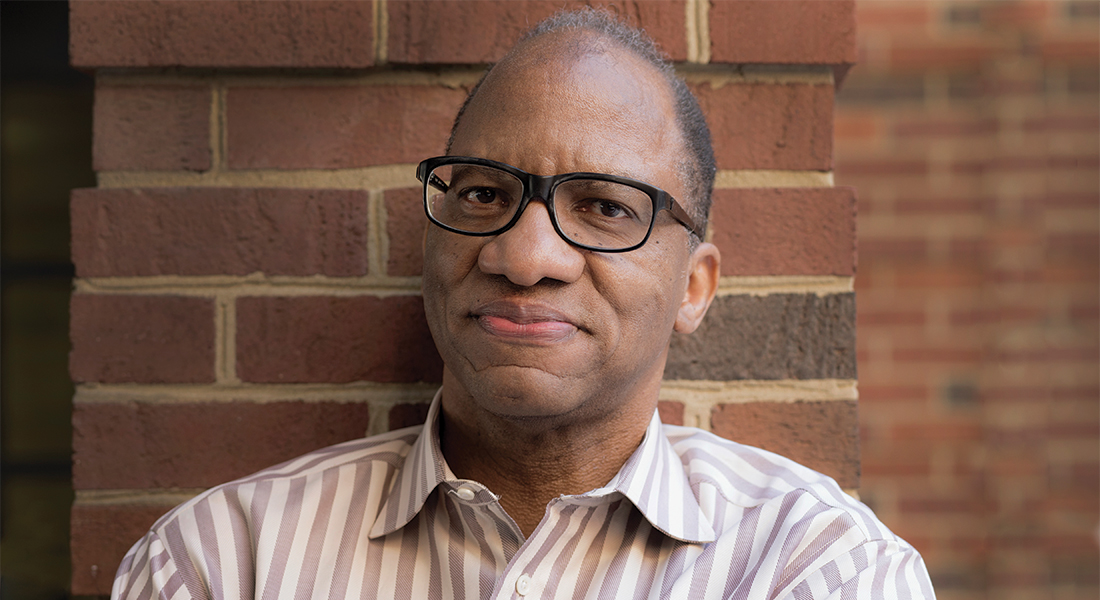 Wil Haygood stands against a brick wall.