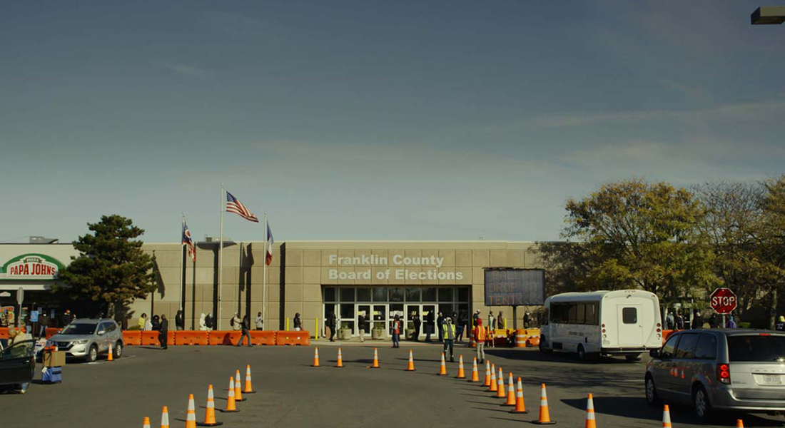 A full shot of the beige concrete exterior of the Franklin County Board of Elections with orange traffic cones remarking the path of entry