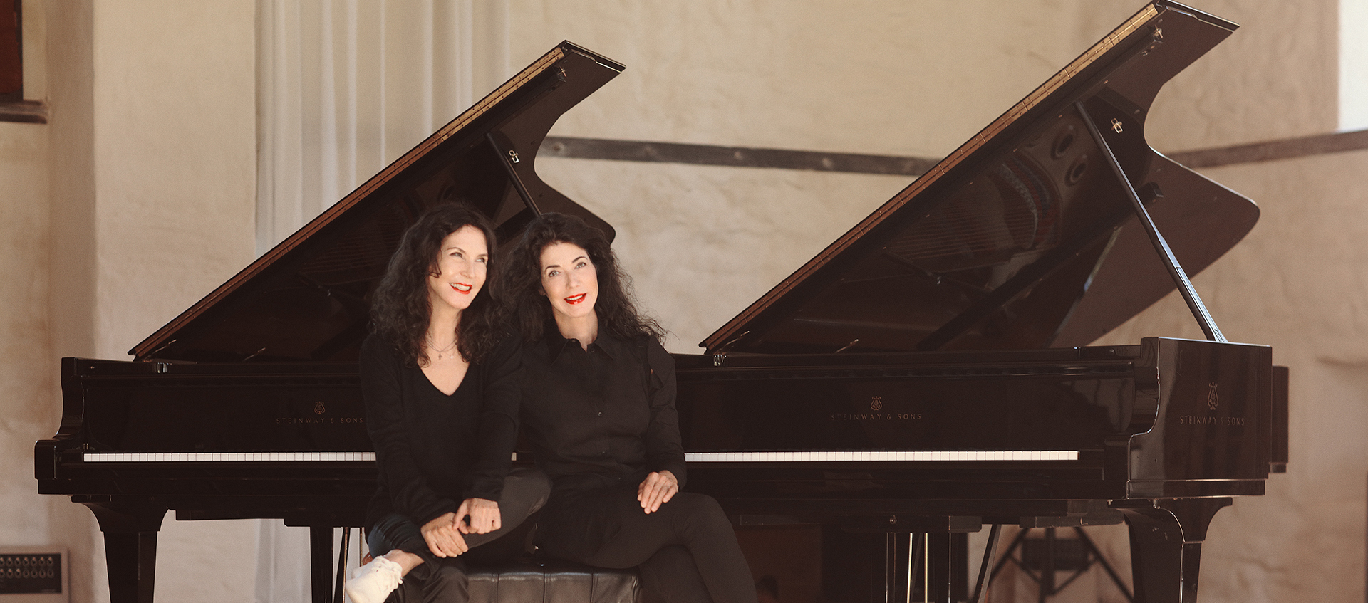 The Labèque Sisters seated in front of two pianos