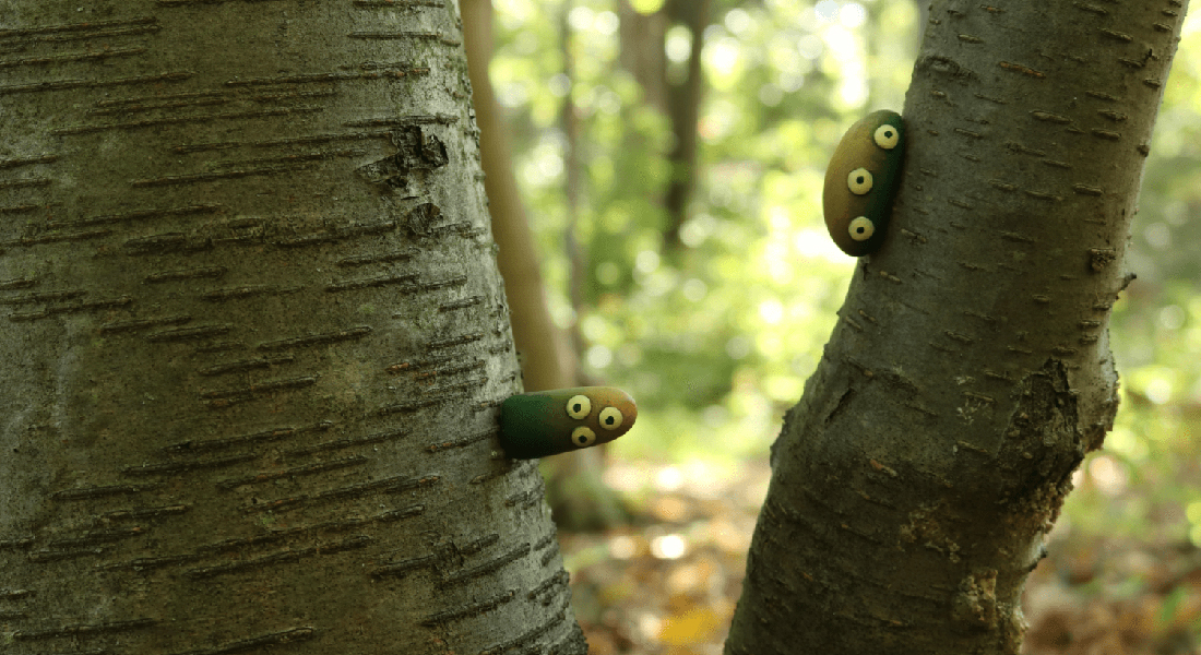 In this claymation still, two three-eyed fungoid blobs peer out while attached to a birch tree