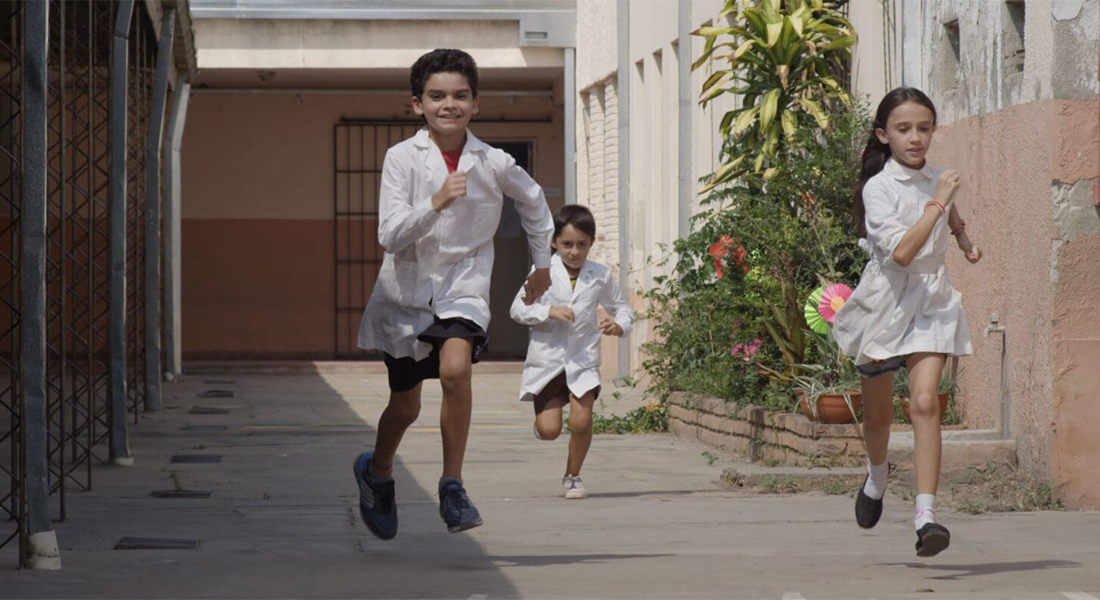 A still of three kids in white shorts running down an alley