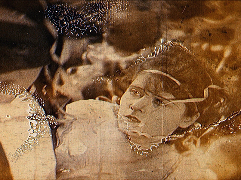 A sepia tinted image of a person looking upwards. The image is cracked and has burns on it