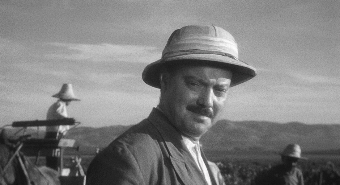 A man with a mustache wears a pith helmet and stares into the distance