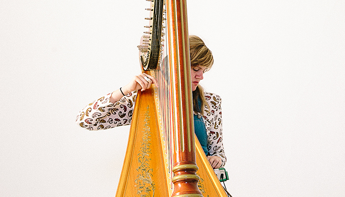 Mary Lattimore playing the harp against a white background