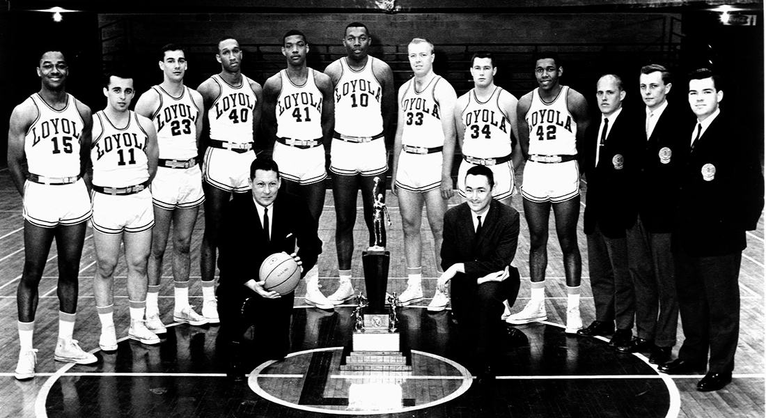 A group photo of the Loyola Rambler standing in front of a trophy