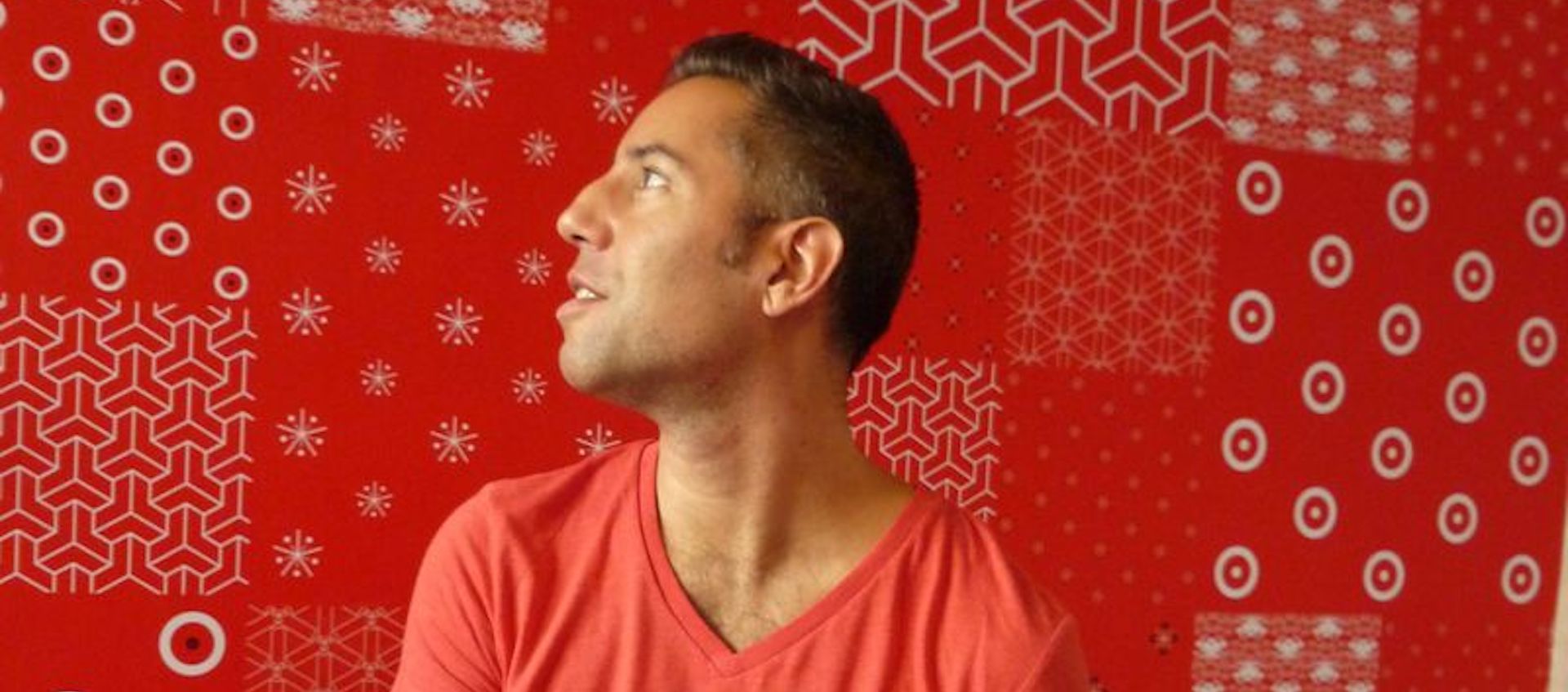 Artist Glenn Belverio, seen in profile against a red bandana-printed backdrop