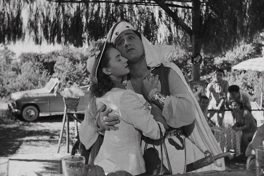 Black-and-white still from The White Sheik featuring Wanda (Brunella Bovo) and Fernando (Alberto Sordin) embracing. Wanda (left) is wearing a dress and hat, and Fernando (right) is wearing a Sheik headdress.