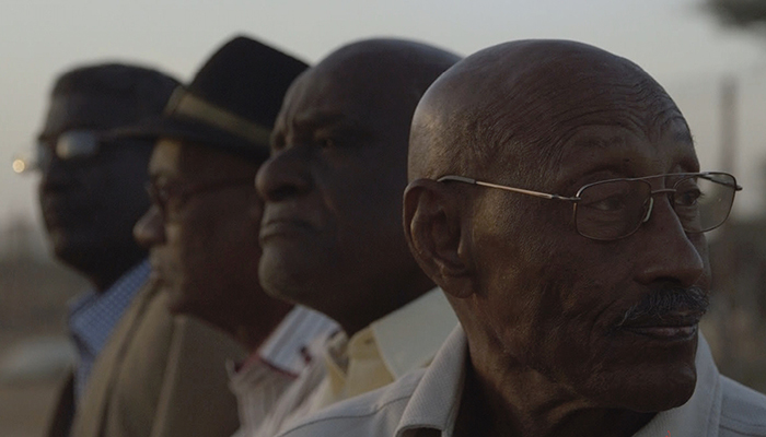 Four men stand in profile