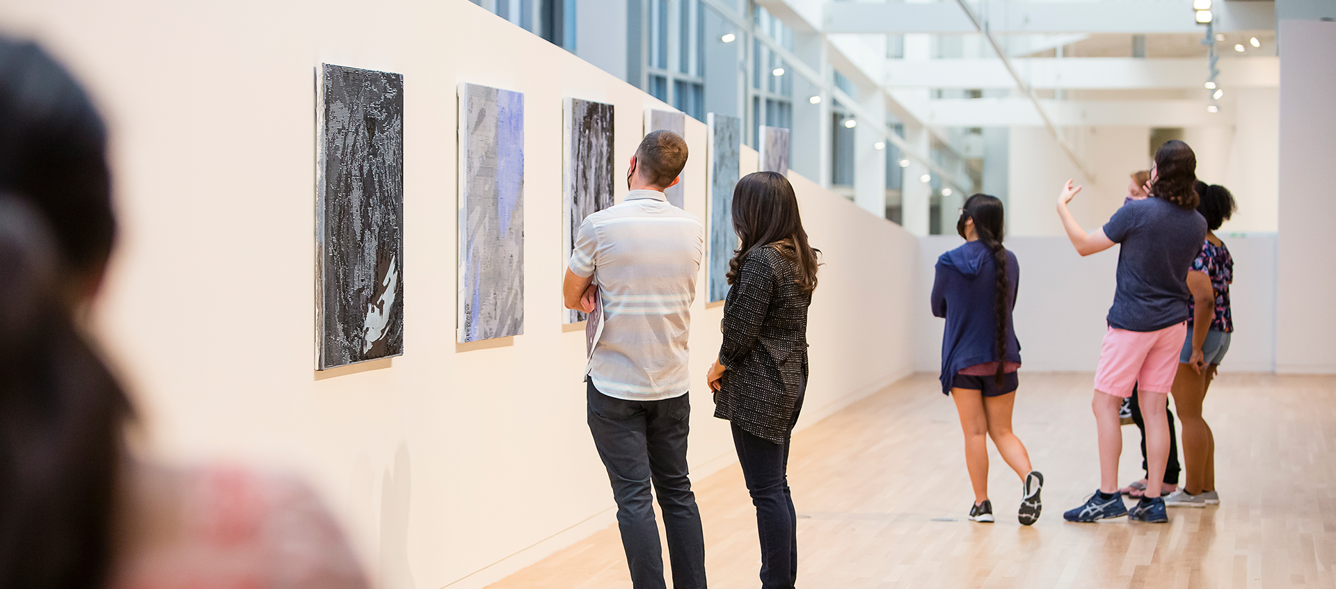 Group of people looking at art hanging on a white gallery wall