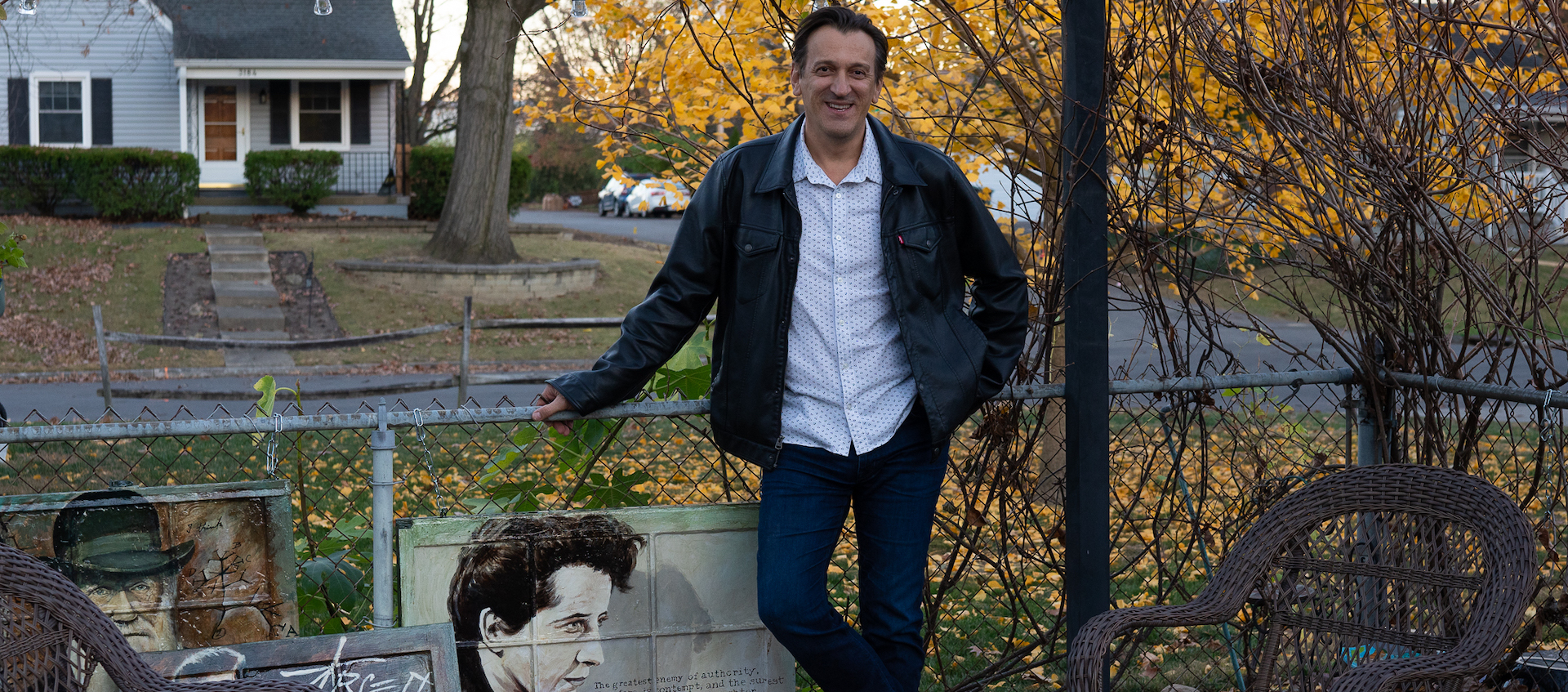 Adin Sadic stands in his yard, surrounded by paintings on glass windows that have been repurposed as canvases. 