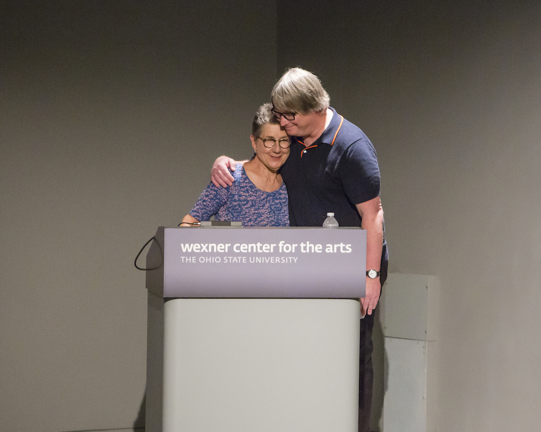 Filmmaker Julia Reichert and Wexner Center Film/Video Director David Filipi embrace at the podium in the Wex's Film/Video Theater.