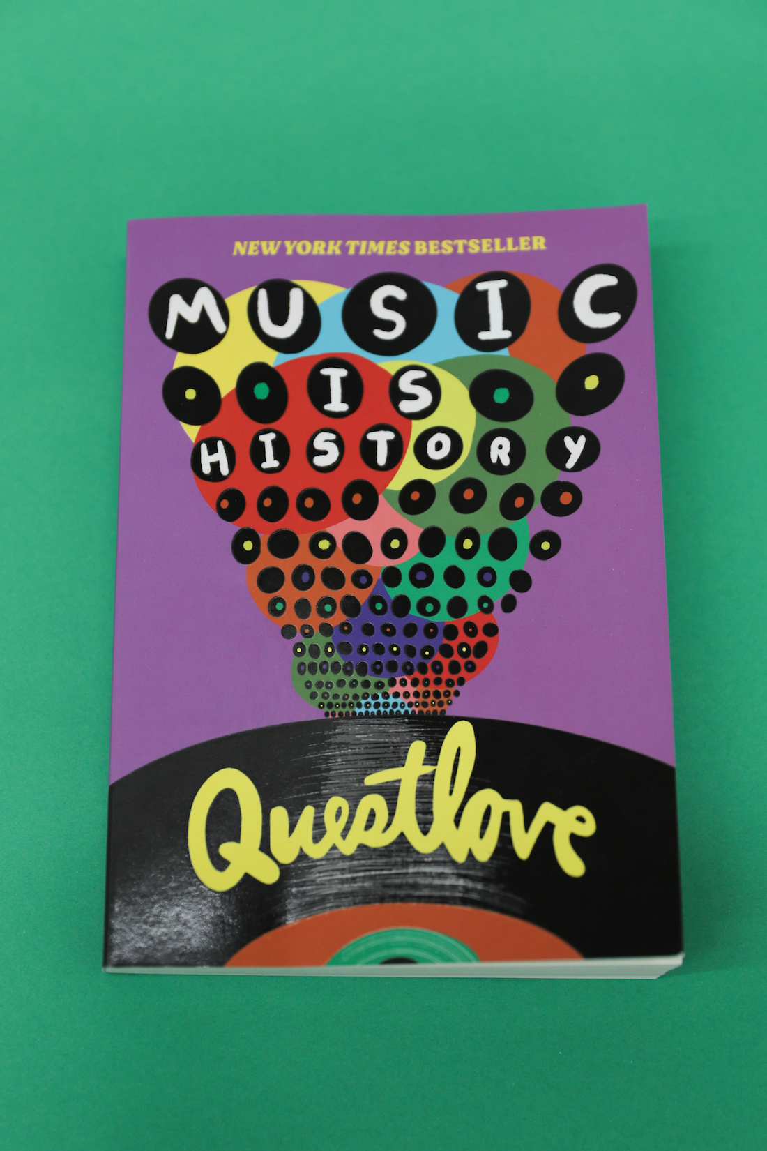 The cover for Questlove's Music is History. It features an illustration of a vinyl record emerging from the bottom and a collage of multicolored circles rising from it like a sun ray.