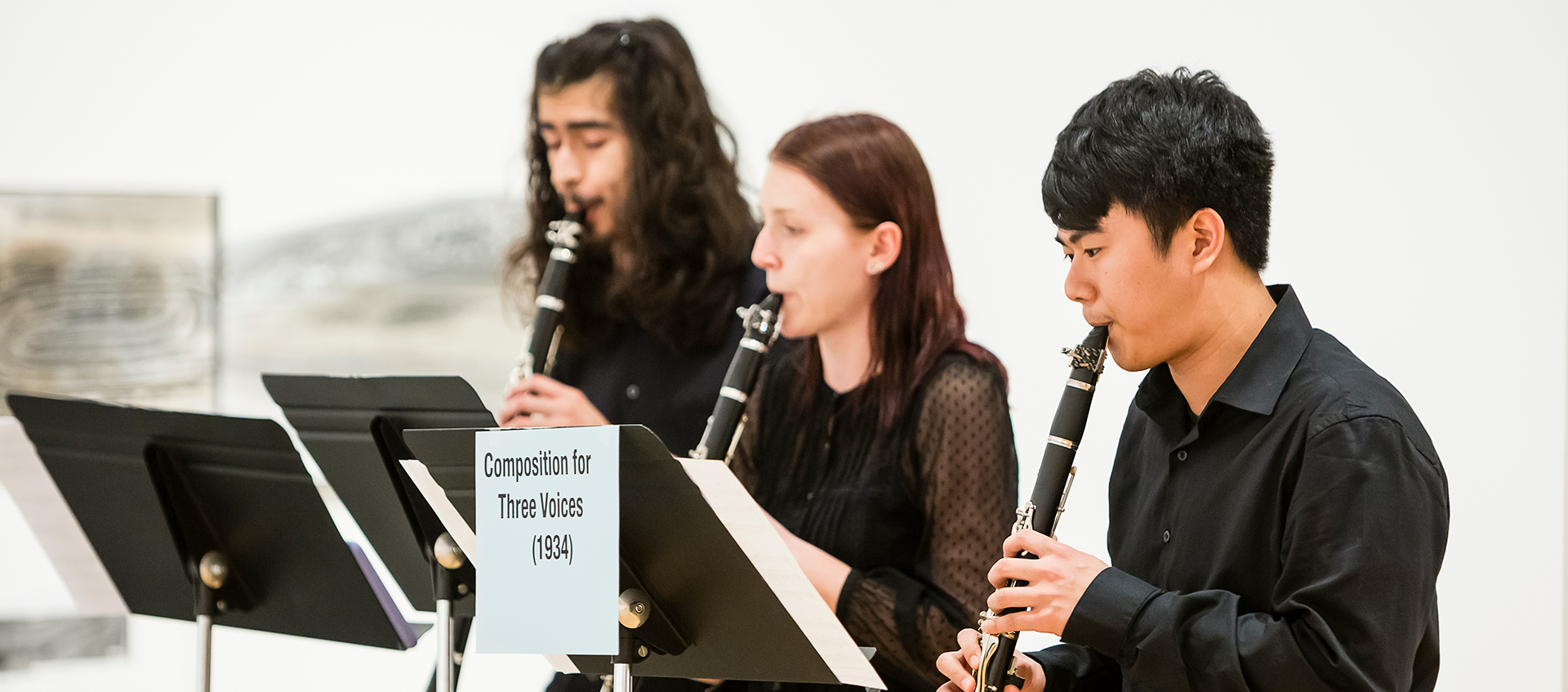 A photograph of three people playing clarinet in a gallery space.