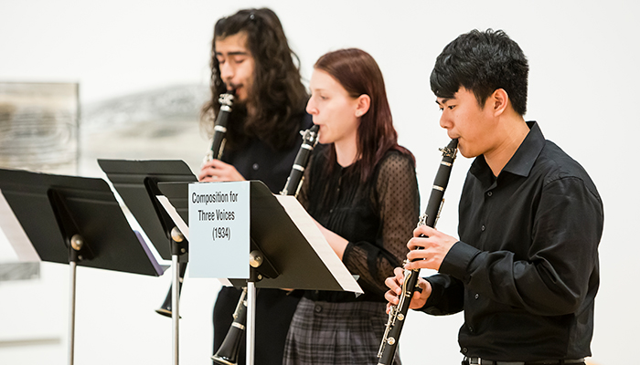 A photograph of three people playing clarinet in a gallery space.