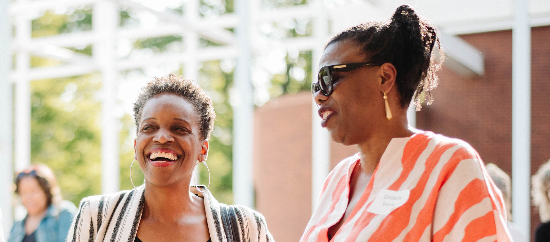 Two women are caught mid conversation. Both are smiling.