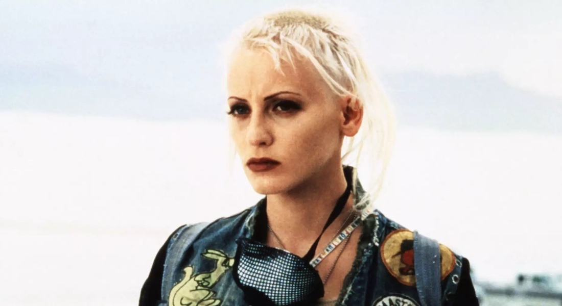 A woman with close-cropped platinum blonde hair looks off into the distance.