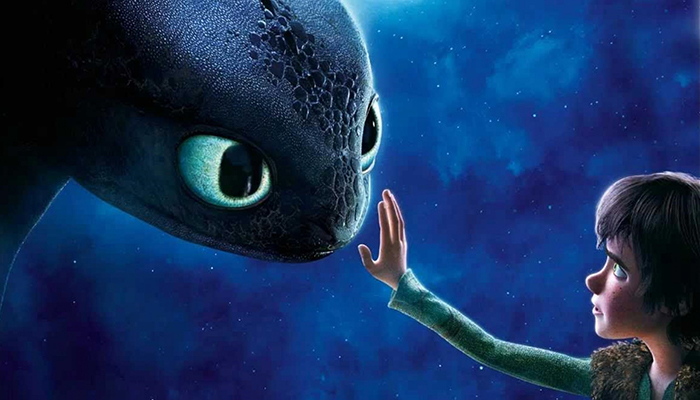 A young cartoon boy is holding up his hand to touch the nose of a large cartoon dragon. The sky behind them is a dark blue and filled with stars. 